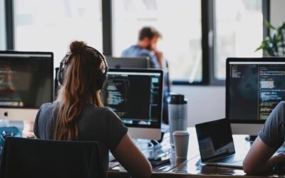 Person wearing headphones working on computer coding in a modern office environment, illustrating website design and development for small business growth.